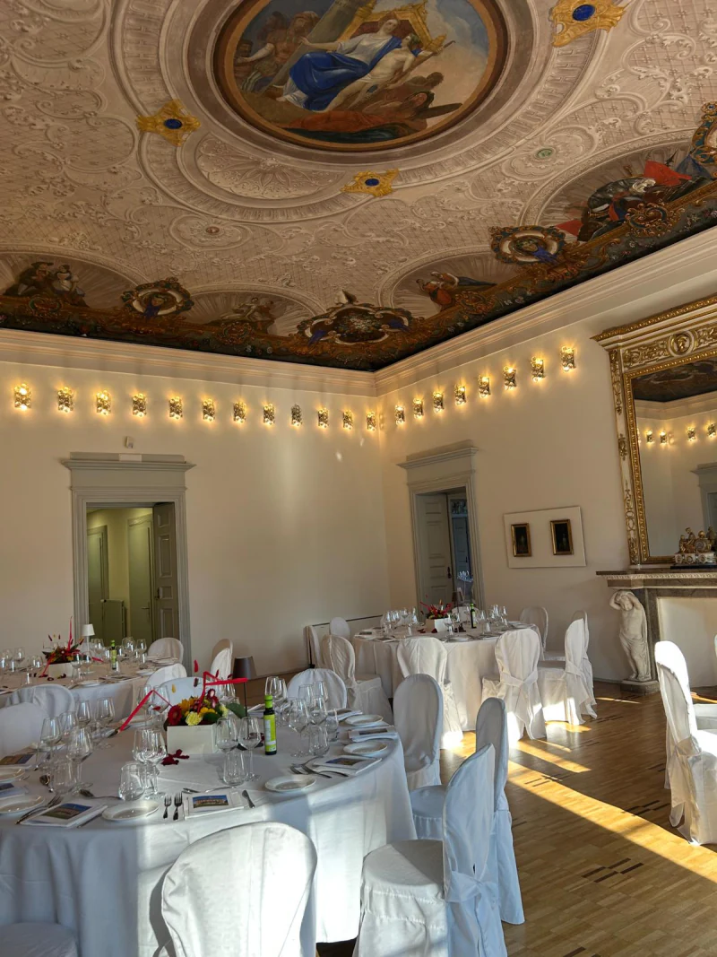 Tables set in a dining room with a frescoed ceiling